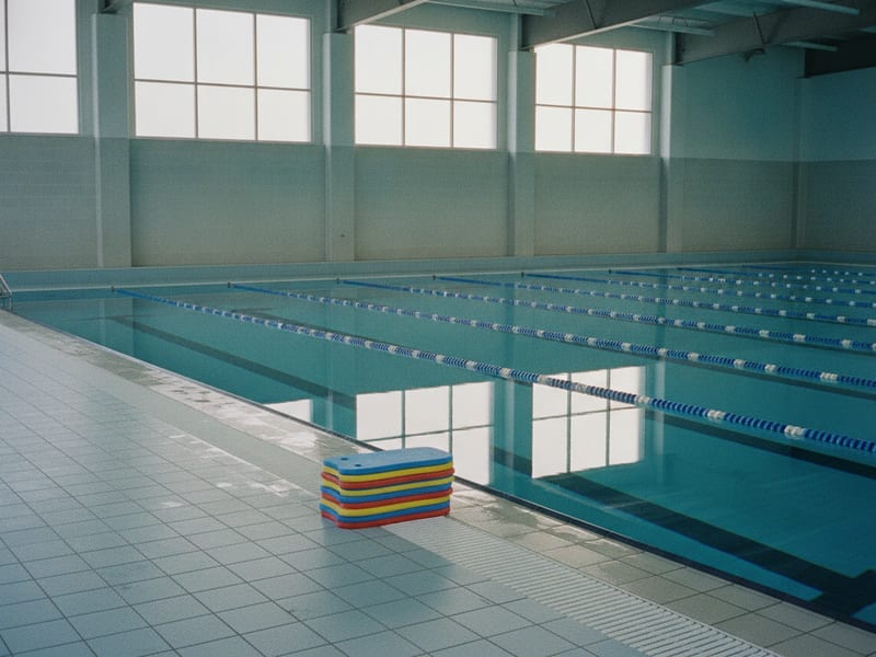 Empty lanes at the aquatic centre, kickboards stacked on the tiles